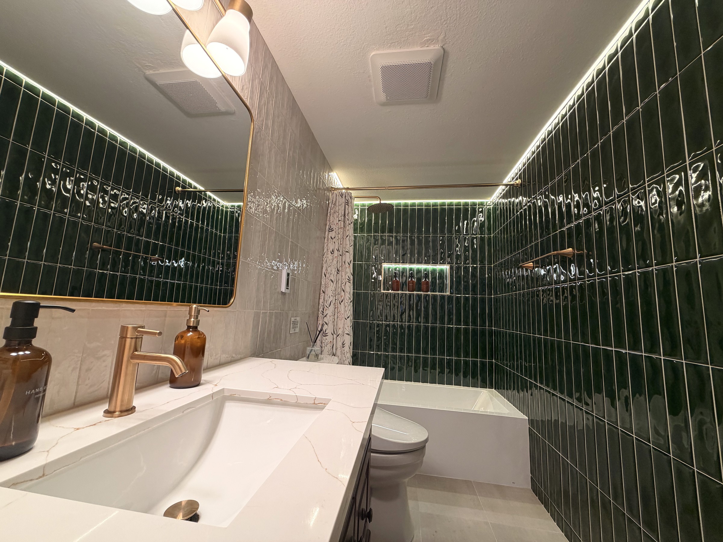 Bath one — emerald zellige tile, brass fixtures, soaking tub, marble vanity