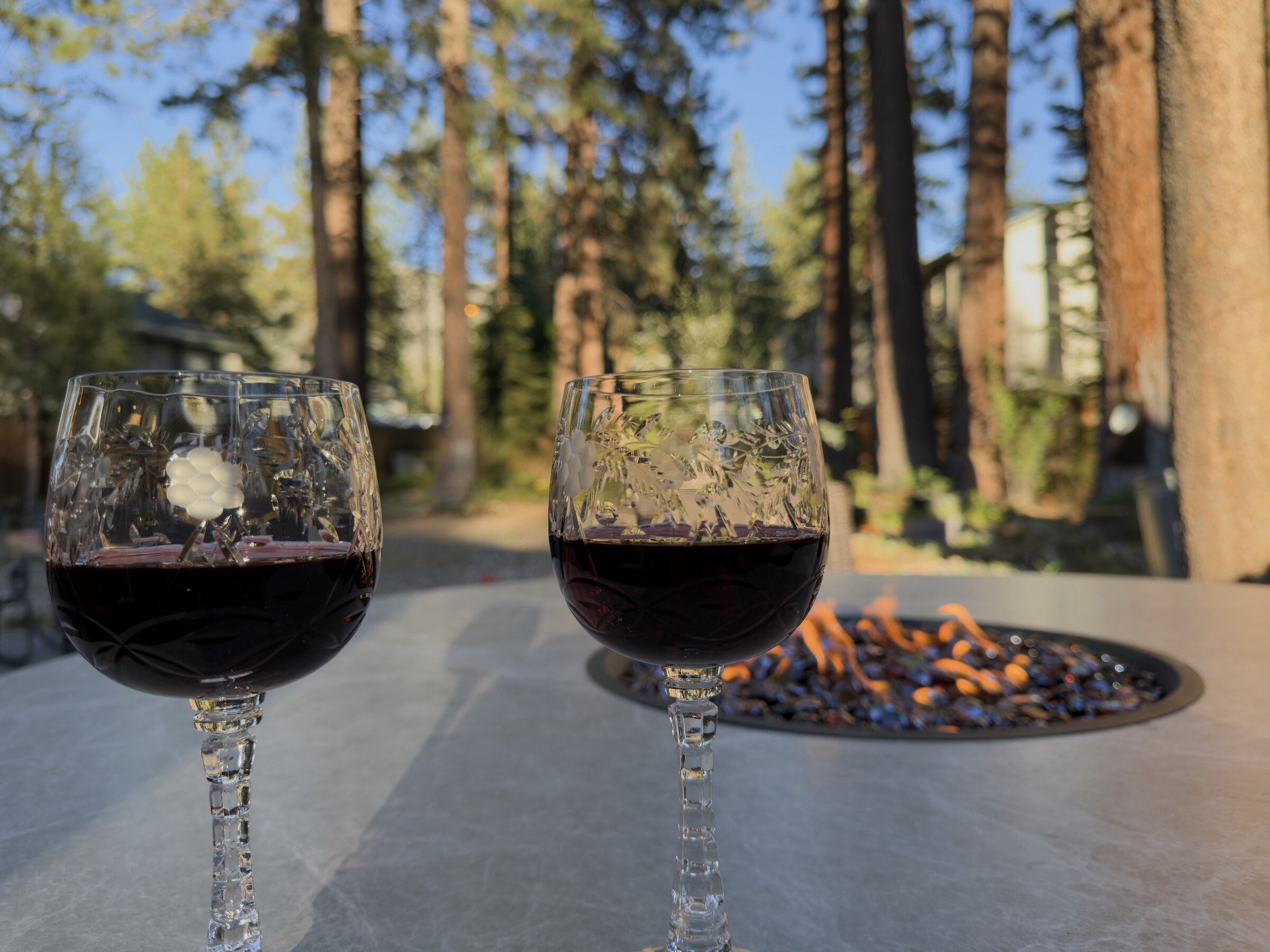 Patio fire-pit table at golden hour, ringed by tall pines